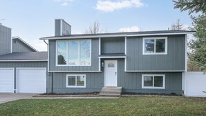 Ein zweistöckiges Haus mit Eingangstür, zwei Garagentoren und einem kleinen Vorgarten.