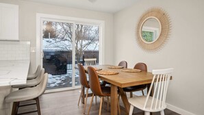 A dining area with a wooden table, four chairs, and a large window.