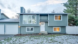 A two-story house with a garage, a front porch, and a snow-covered lawn.