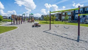 A playground with various play structures, a picnic table, and a sand area. - Charming Legal Suite Ensuite BSMT, Two Beds, Two Baths (Calgary)