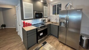 A compact kitchen with a microwave, stove, sink, and refrigerator. - Charming Legal Suite Ensuite BSMT, Two Beds, Two Baths (Calgary)