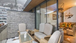 Una sala de estar moderna con un muro de vidrio, un muro de piedra y un techo de madera.