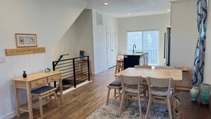 A modern kitchen with a large island, wooden flooring, and a dining area with a round table and chairs. - Skip Rock Retreat | Near SLC | Cozy Mid-Term Stay (South Jordan)