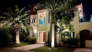 A two-story building with a well-lit entrance, a visible door, and a balcony.