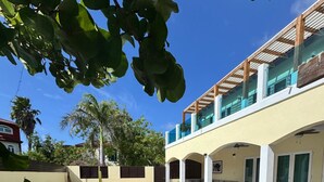Une piscine avec des chaises longues, un patio couvert et un bâtiment à deux étages doté de balcons.