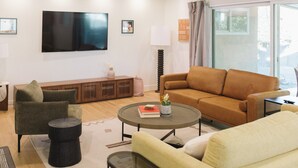Una sala de estar moderna con un sofá, un sillón, una mesa de centro y un televisor de pantalla plana montado en la pared.