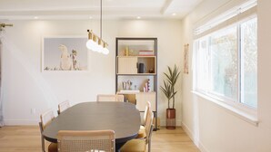 Un comedor con una mesa redonda, sillas, una estantería y una planta en maceta.