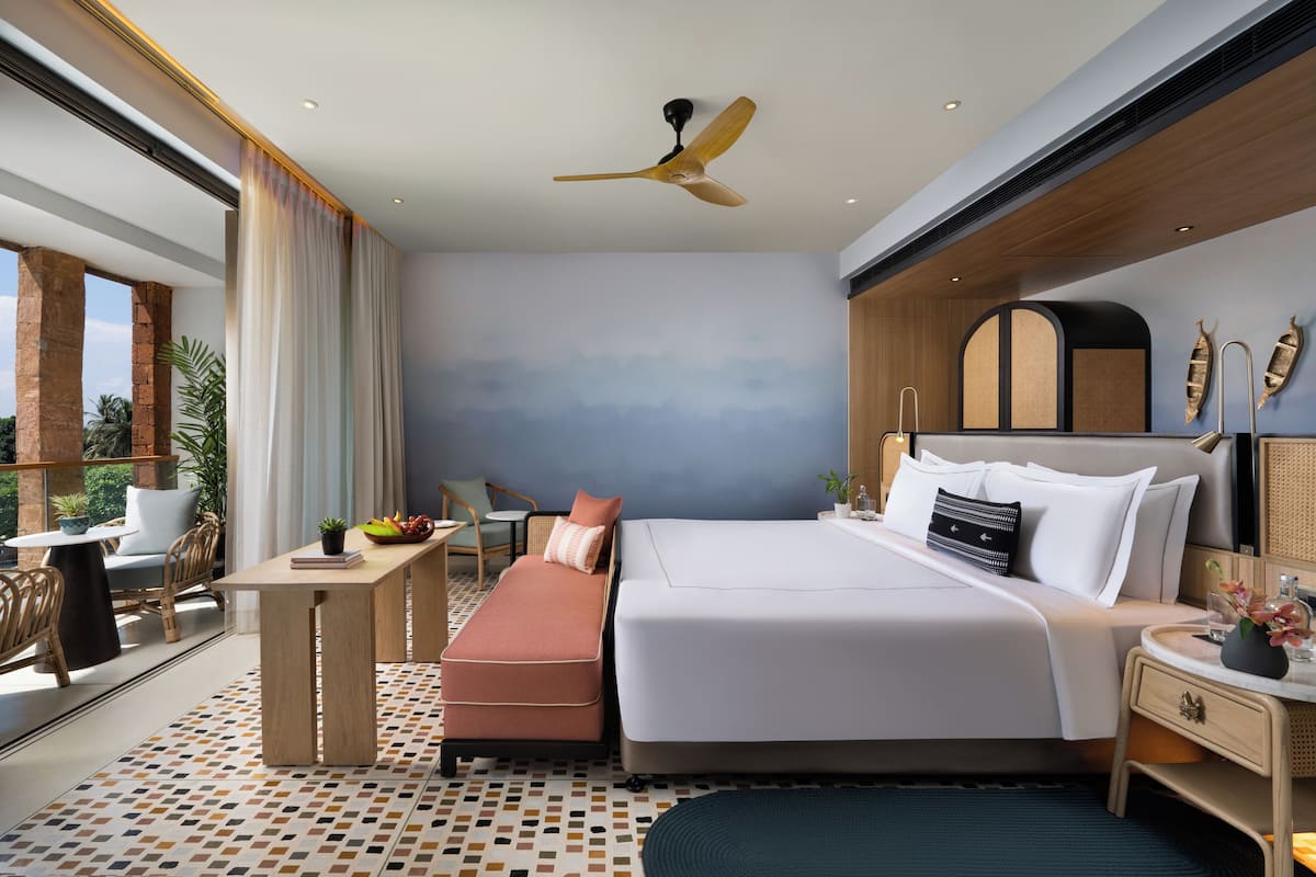 A modern hotel room with a large bed, a desk, and a seating area.