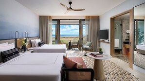 Quarto de hotel moderno com duas camas, varanda com vista, ventilador de teto e uma pequena mesa com uma planta.