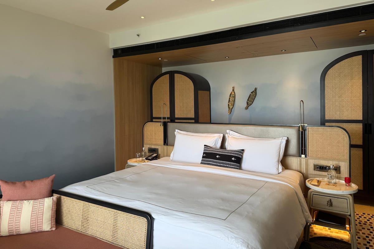 A modern hotel room with a large bed, a ceiling fan, and a wall-mounted TV.