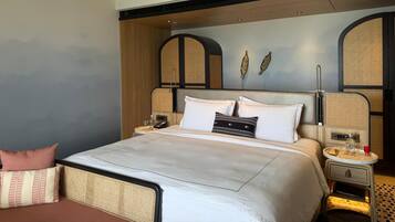 A modern hotel room with a large bed, a ceiling fan, and a wall-mounted TV.