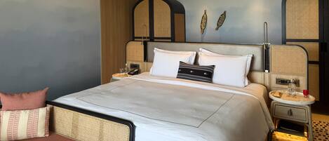 A modern hotel room with a large bed, a ceiling fan, and a wall-mounted TV.