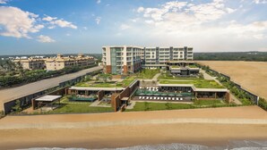 Um hotel moderno com um jardim no terraço, piscina e vista para a praia.