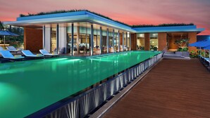 Um hotel moderno com piscina, espreguiçadeiras e deck de madeira.