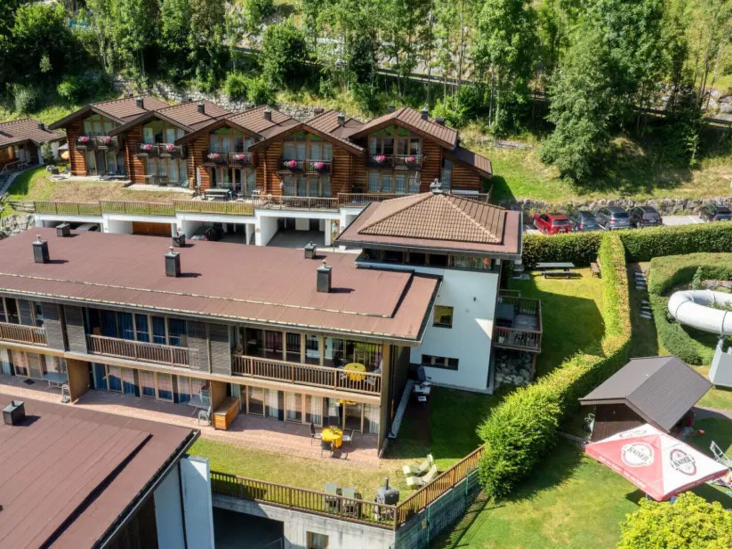Ein mehrstöckiges Hotel mit Balkonen, einem Schwimmbad und einem gepflegten Rasen.