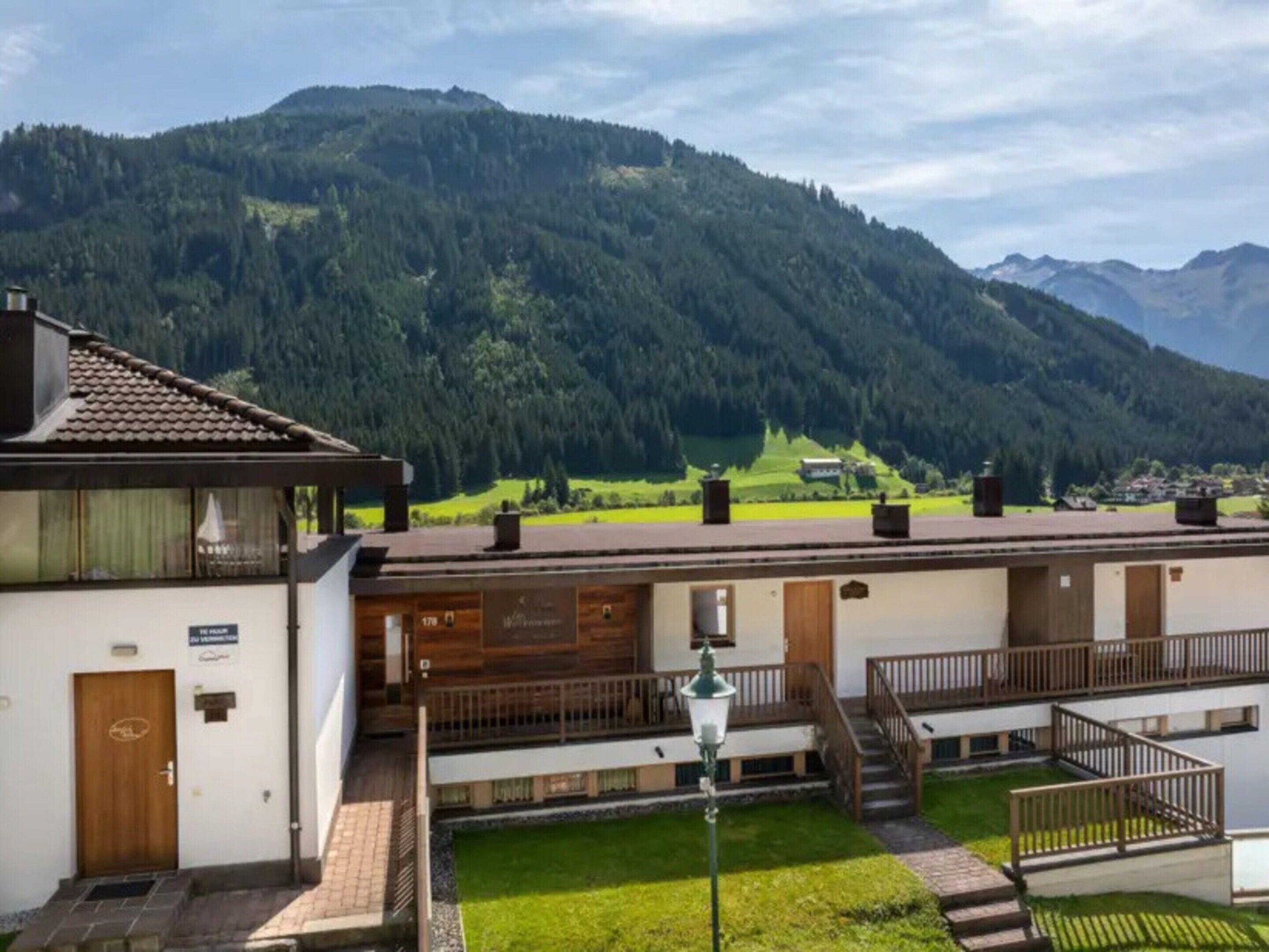 Un hotel con vistas a una cadena montañosa, un área exterior cubierta y un césped bien cuidado.