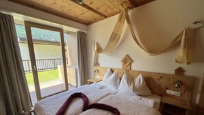 A hotel room with a bed, a nightstand, and a view of the outdoors. - Zirbenholz Alpine Maisonette Stay (Wald im Pinzgau)