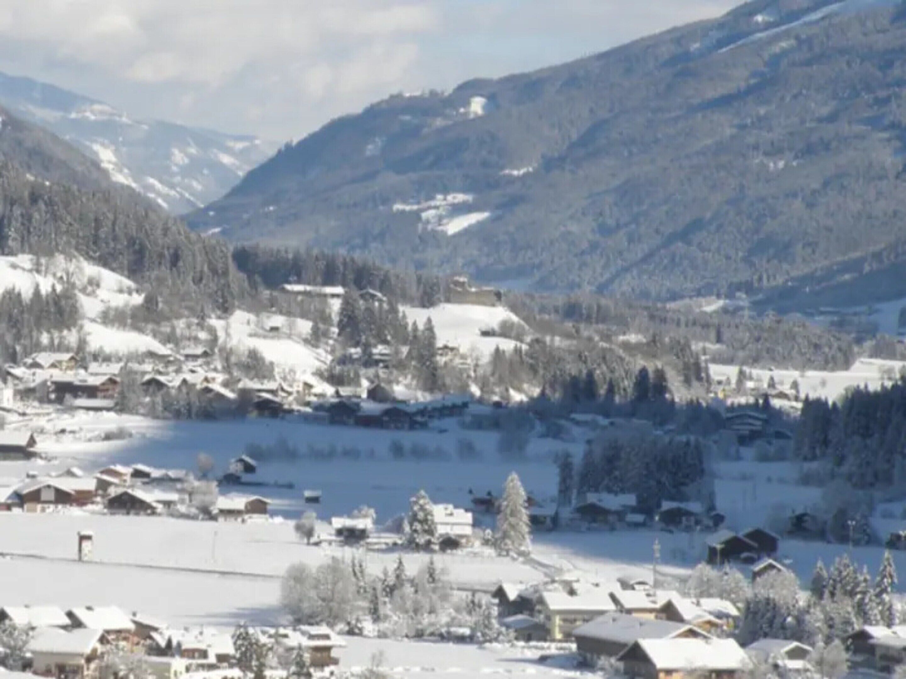 Un pueblo cubierto de nieve con casas y una montaña al fondo.