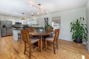 Une cuisine moderne dotée d’un îlot central, d’appareils électroménagers en acier inoxydable et de chaises en bois.
