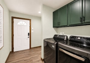 A laundry room with a washing machine, dryer, and green cabinets. - Reverie Reserve—5BR on Private Acre, North Keller (Keller)