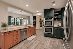 A modern kitchen with a built-in oven, stainless steel appliances, and a large refrigerator. - Reverie Reserve—5BR on Private Acre, North Keller (Keller)