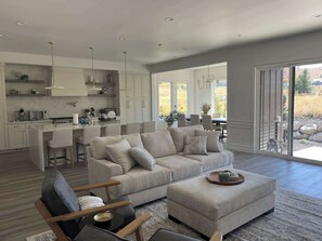 A spacious living area with a large beige sofa, a wooden coffee table, and a modern kitchen in the background. - NEW Luxury Home super comfy By Snowbasin & Pow Mow - 30-night minimum stay (Huntsville)