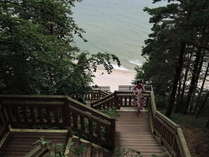 A wooden staircase leading to a beach, surrounded by dense trees. - Comfortable Apartment With a sea View (Miedzyzdroje)
