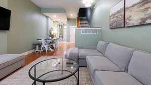 A modern living room with a grey sofa, a glass coffee table, and a staircase leading to an upper level. - Spacious 4-bedroom townhome in St. Louis  (St. Louis)