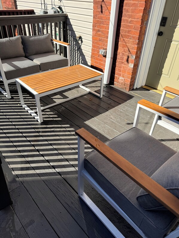 A wooden deck with outdoor furniture, including a bench and a sofa.