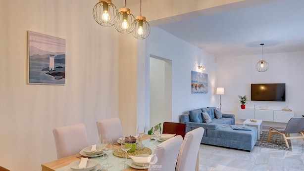 Ein modernes Wohnzimmer mit Essbereich, einer Couch, einem Fernseher und einem Gemälde an der Wand.