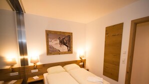 Ein Hotelzimmer mit einem hölzernen Bett, zwei Nachttischlampen, einem gerahmten Bild an der Wand und einer Holztür.
