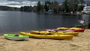 Una playa arenosa con varias kayaks alineadas.