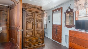 Una habitación con un armario de madera, un televisor y un espejo en la pared.