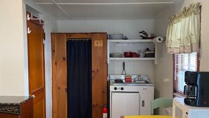 Een kleine keuken met een fornuis, magnetron en kleine koelkast.