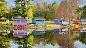 Een rij kleurrijke huizen aan een rustig meer, met weerspiegelingen.