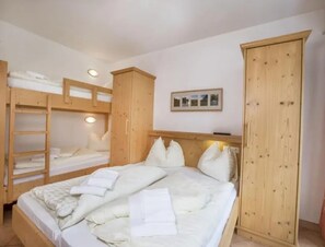 A room with a bunk bed, wooden wardrobe, and a framed picture on the wall.
