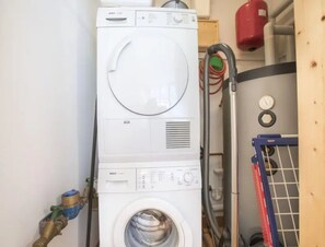 A white Bosch washing machine in a laundry room with a hose and a red fire extinguisher on the wall. - Maisonette Stay for 8 Guests (Wald im Pinzgau)