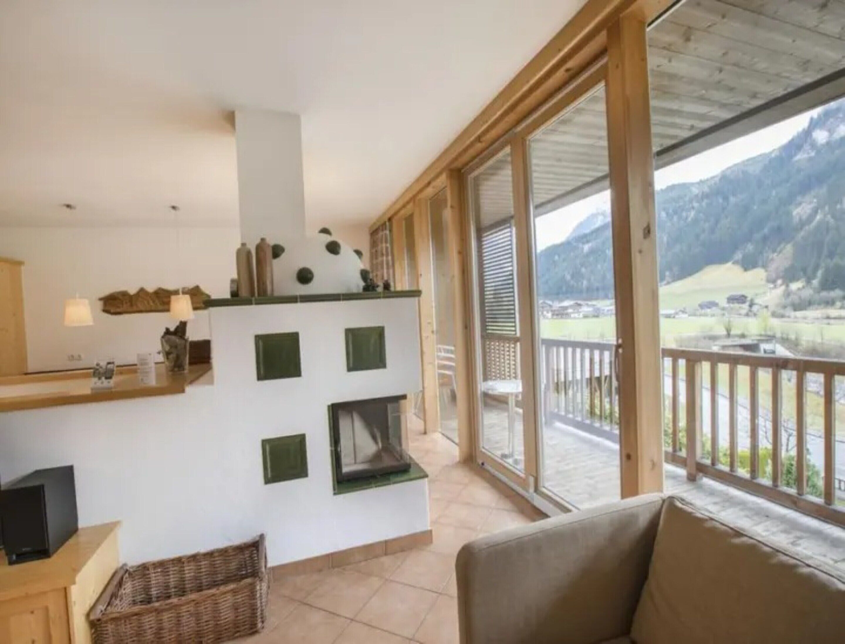 A room with a kitchen area, a sofa, and a balcony with a mountain view.