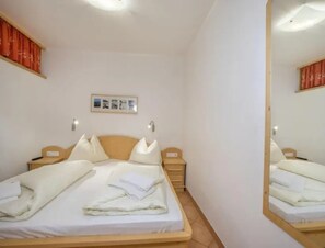 A hotel room with a bed, bedside tables, a mirror, and a framed picture on the wall. - Maisonette Stay for 8 Guests (Wald im Pinzgau)