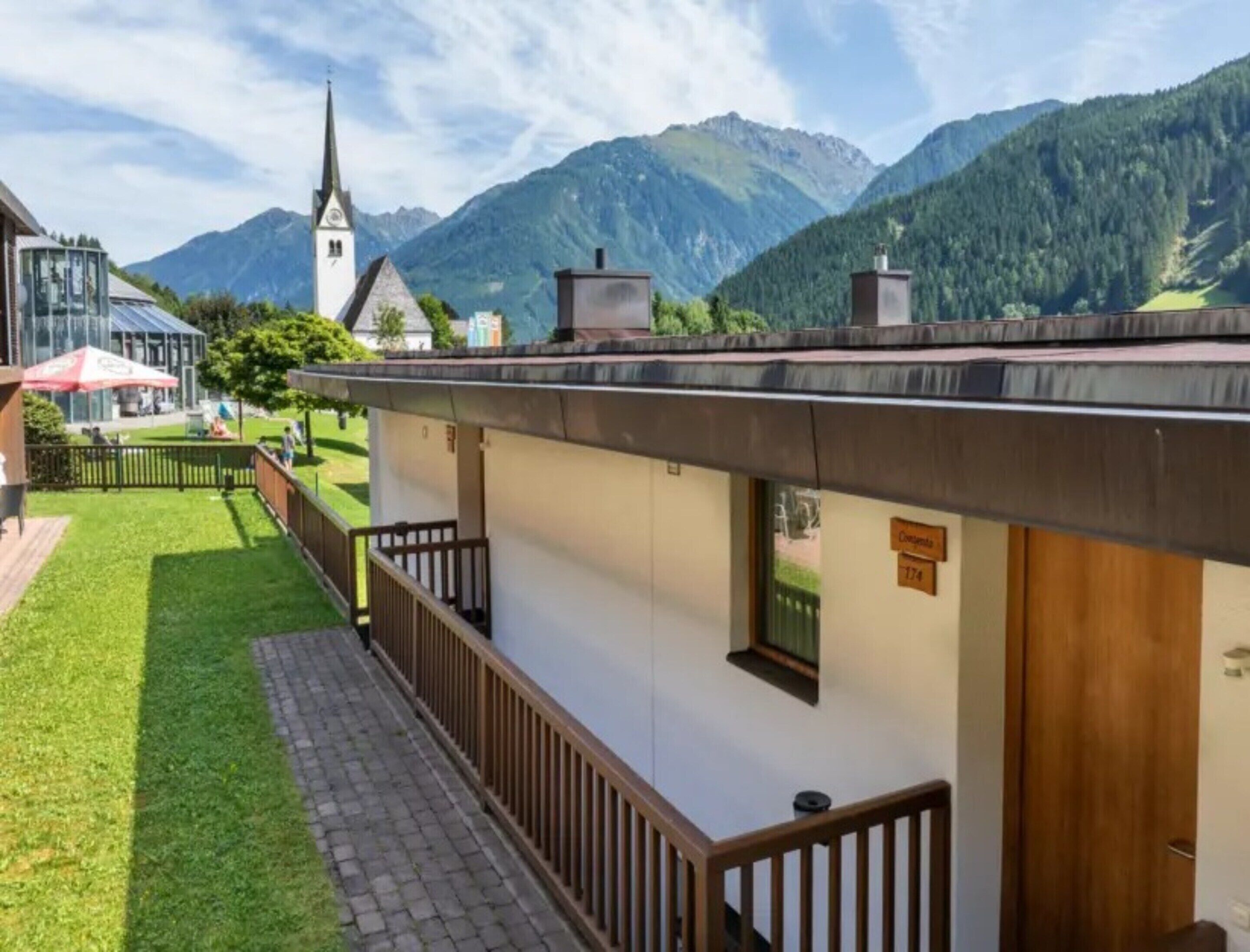 A hotel with a mountain view, a church, and a paved walkway.