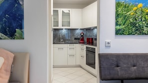A modern kitchen with white cabinets, a red coffee machine, and a tiled floor. - Apartment 'Fewo-Gottmadingen' with Wi-Fi (Gottmadingen)