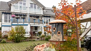 En fugleholder i en have med et hus i baggrunden.