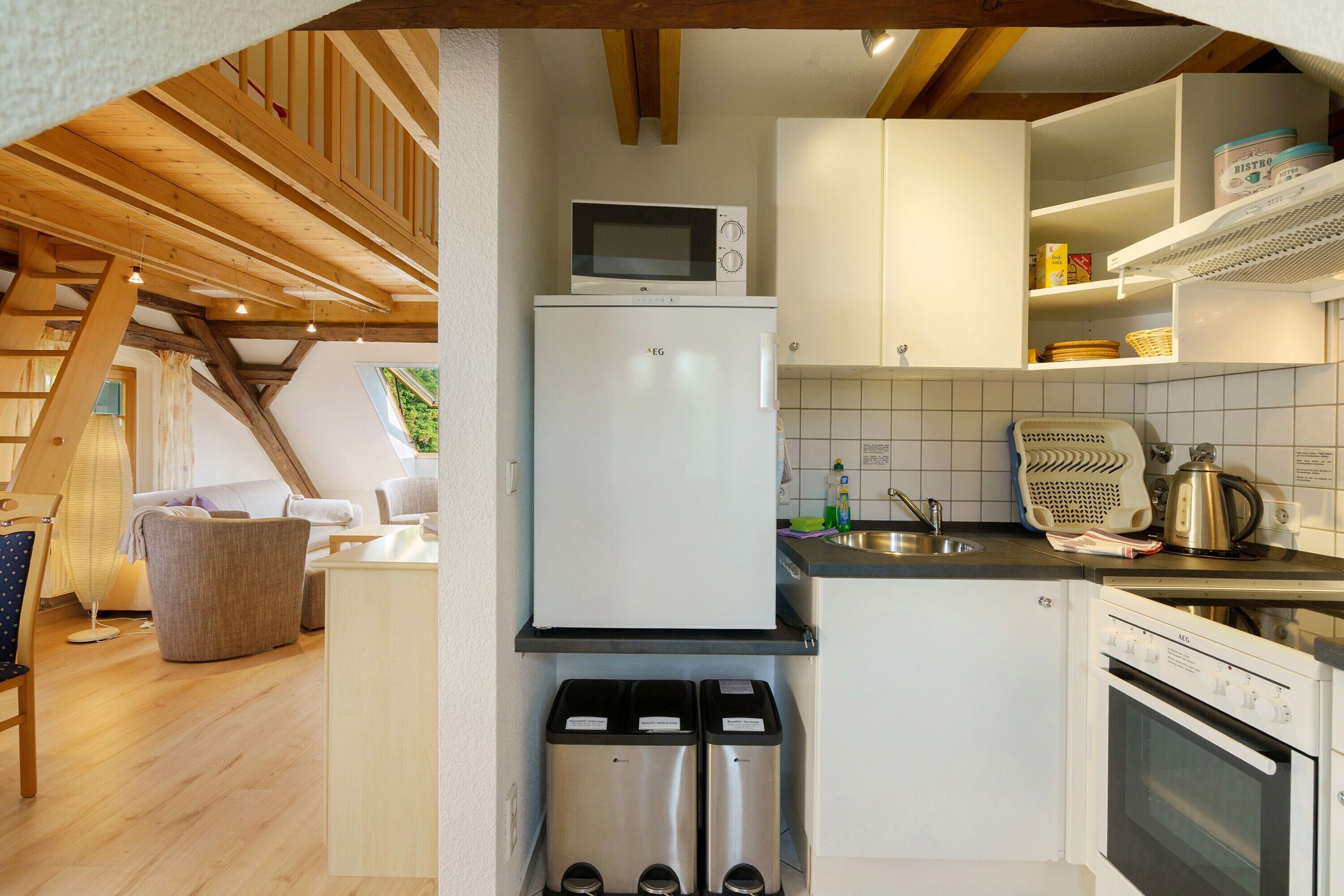 Eine kompakte Küche mit Mikrowelle, Kühlschrank und Herd. Ein Spülbecken und ein Fenster befinden sich über dem Spülbecken.