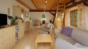 A cozy living room with wooden beams, a sofa, a table, and a television. - Apartment 'Gutshof Lesch - Ferienwohnung 2' with Private Garden and Wi-Fi (Chemnitz)