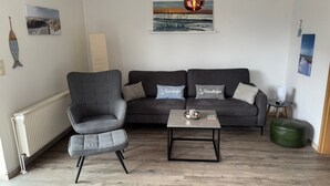 Un salon avec un canapé gris, un fauteuil gris, une table basse et une suspension.