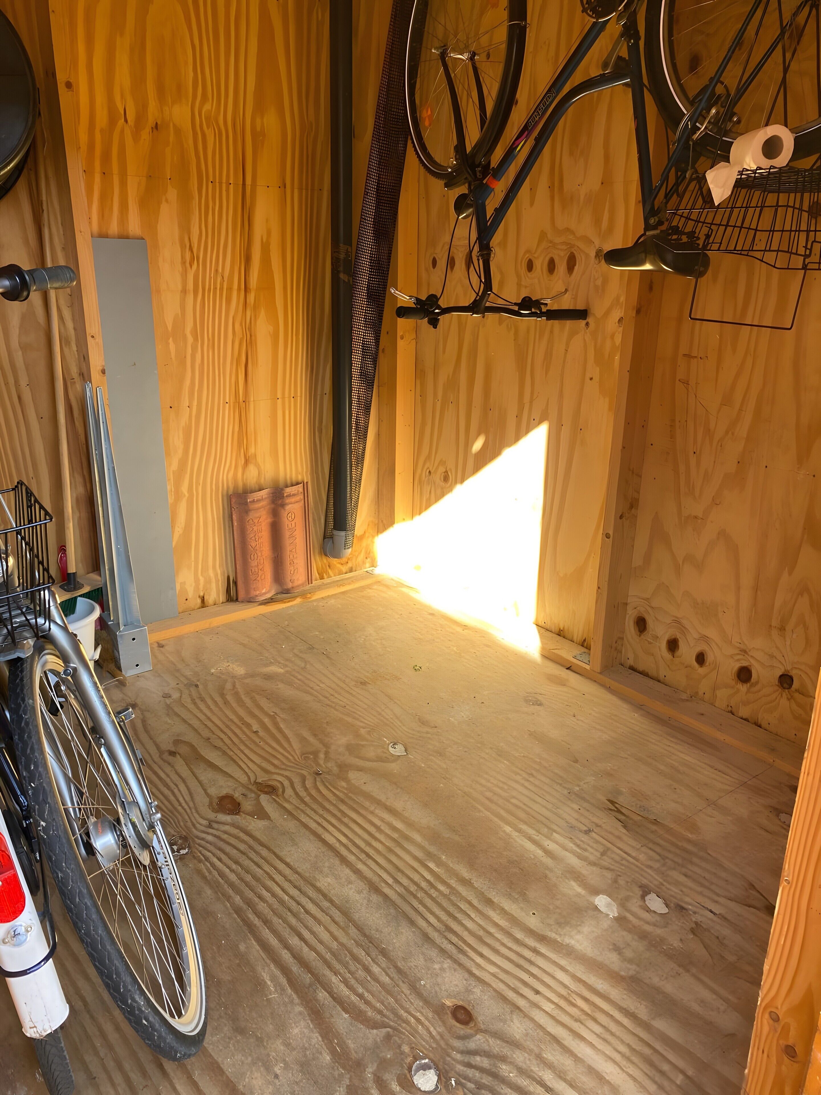 Ein Zimmer mit Holzboden, einem Fahrrad und einem Metallgestell.