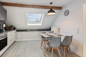 Une cuisine moderne avec une lucarne, une table à manger avec des chaises et une horloge au mur.