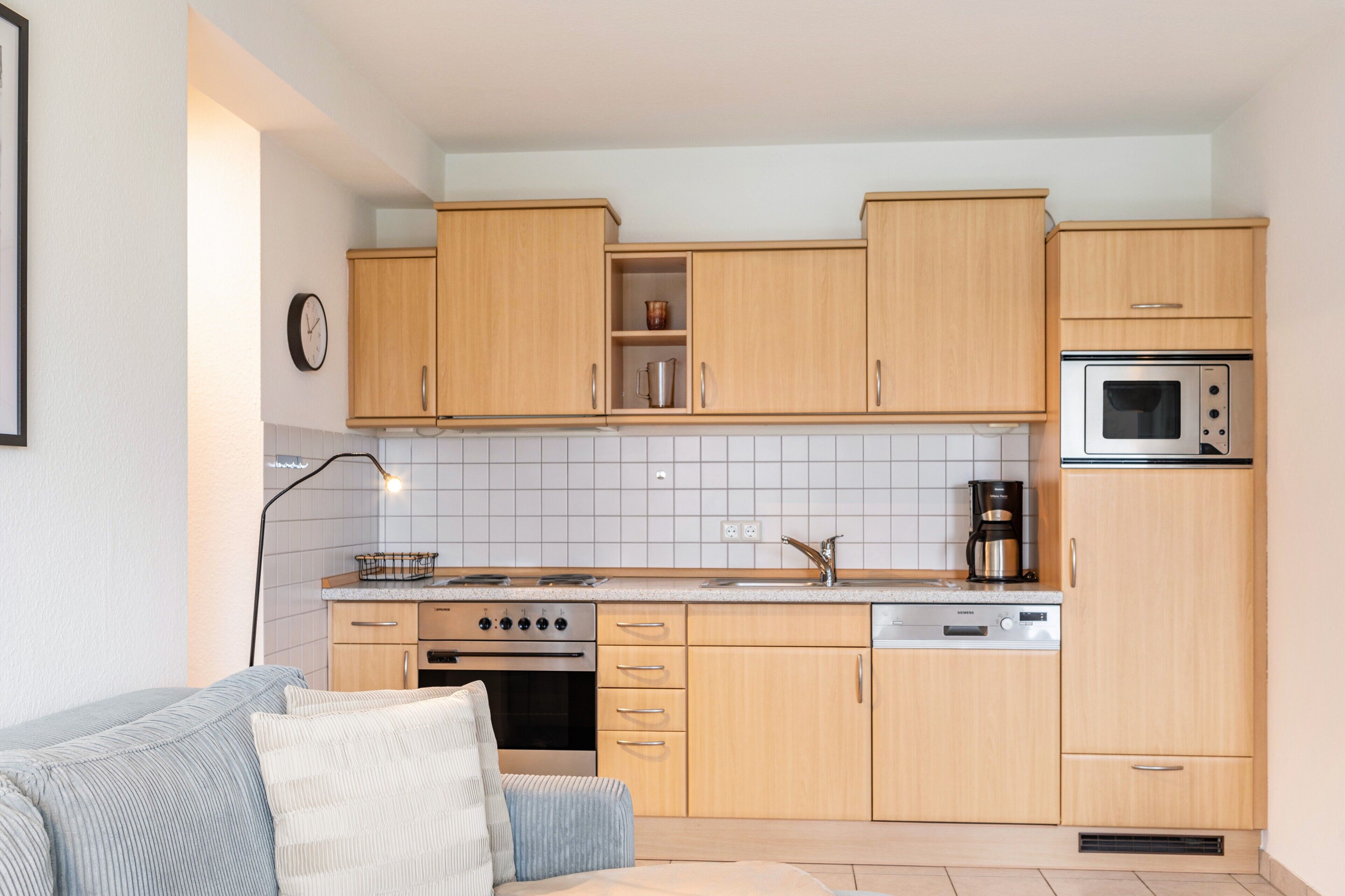 Une cuisine moderne avec des meubles de rangement en bois, un four encastré, un four à micro-ondes et une machine à café.