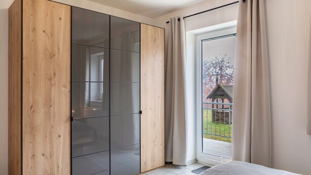 Une pièce dotée d’une armoire à portes coulissantes, d’une porte en verre et donnant sur un jardin.