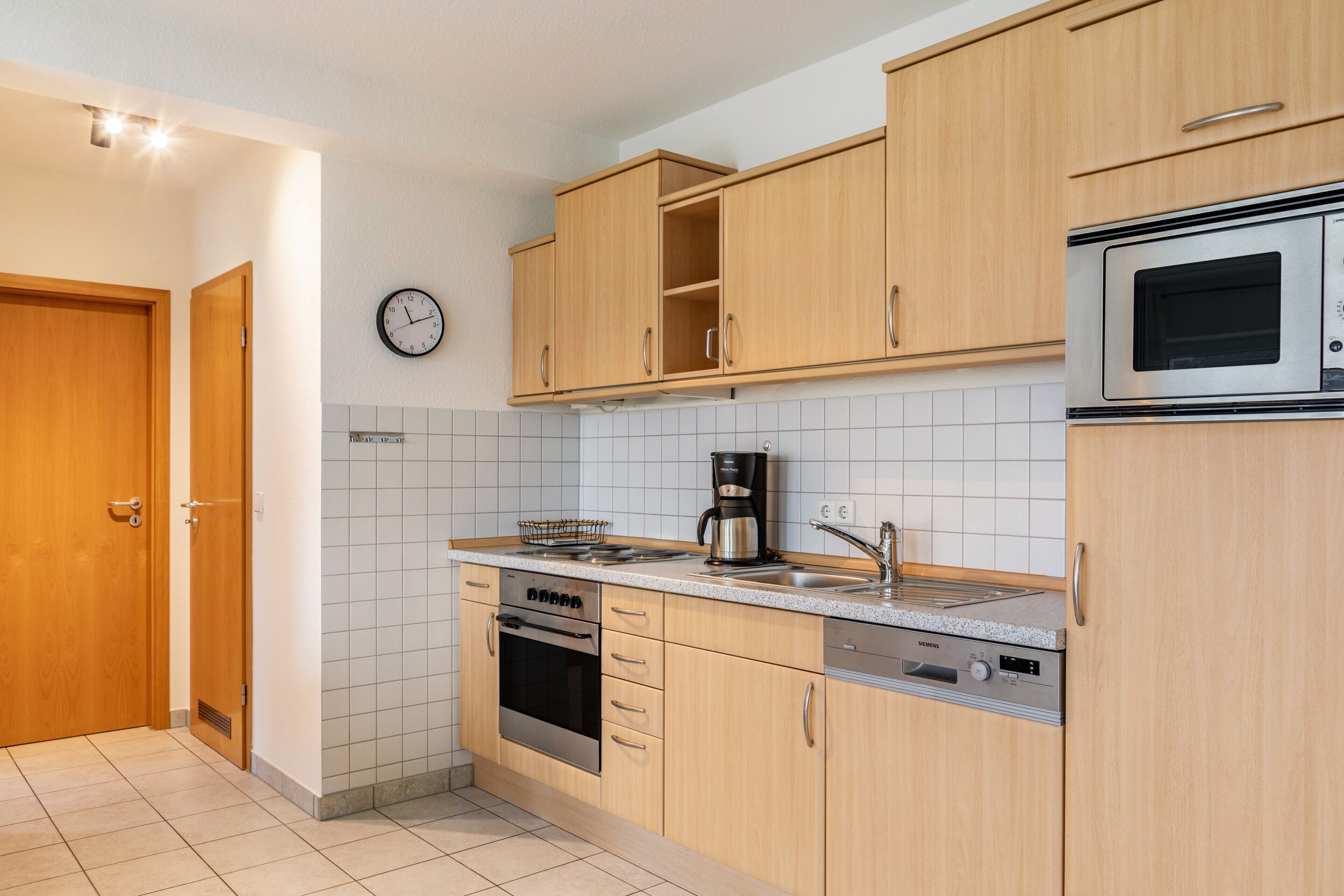 A kitchen with wooden cabinets, a stainless steel oven, a coffee maker, and a microwave.